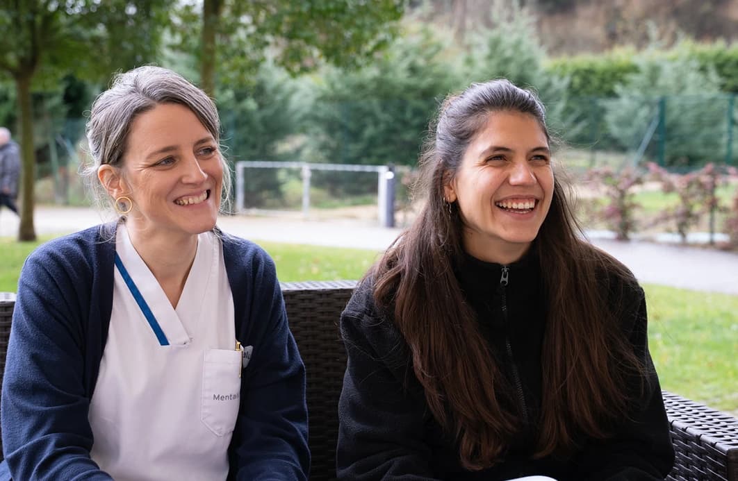 Imagen de dos mujeres sonriendo sentadas en un sofá.