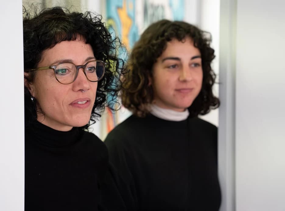 Imagen de dos mujeres mirando a través de una puerta.